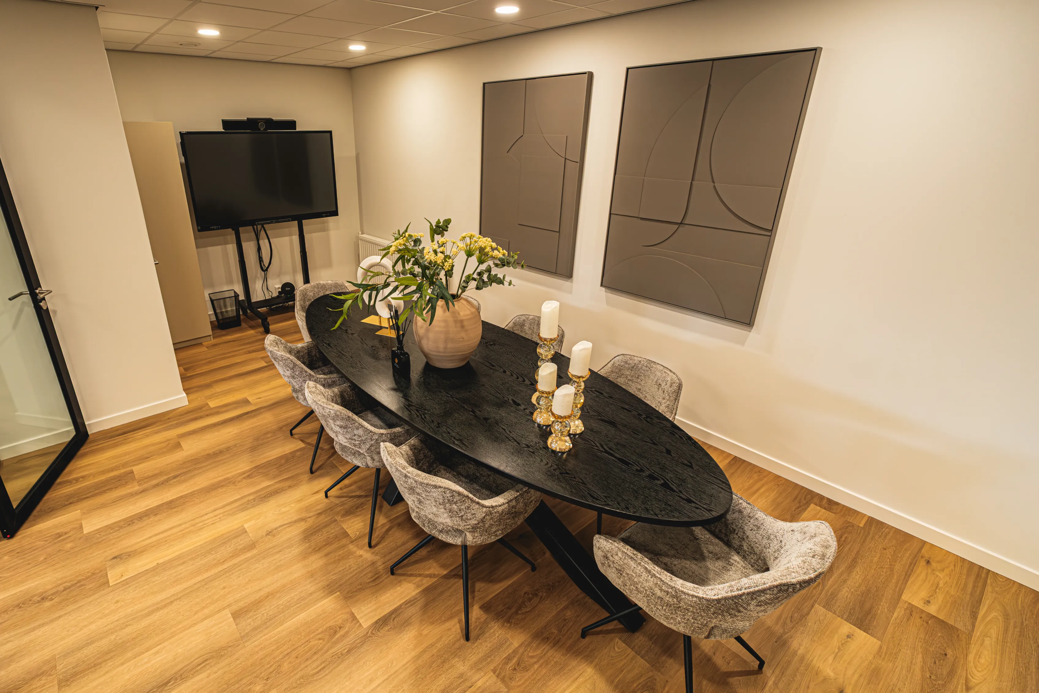Vergaderruimte met ovale tafel, scherm en luxe stoelen